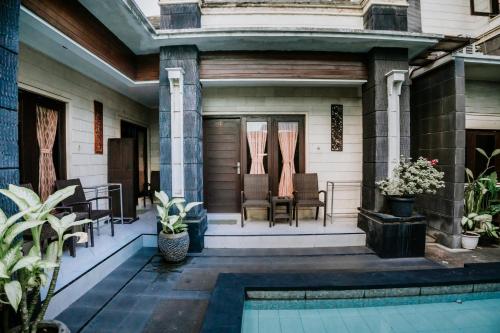 a house with a porch with chairs and a pool at Denays Guest House Jimbaran in Ngurah Rai International Airport