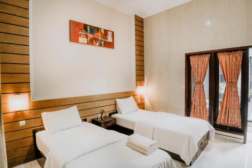 a room with two beds and a window at Denays Guest House Jimbaran in Ngurah Rai International Airport