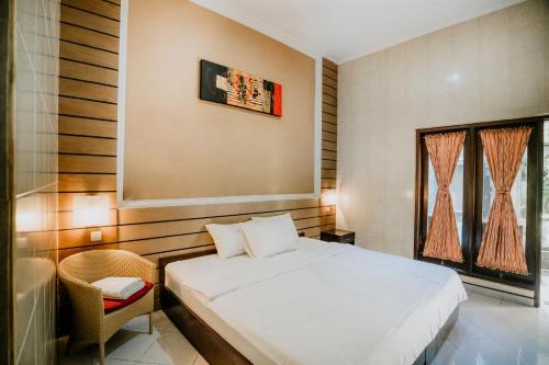a bedroom with a white bed and a window at Denays Guest House Jimbaran in Ngurah Rai International Airport