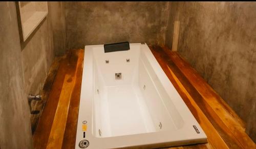 une baignoire blanche dans une pièce avec un plancher en bois dans l'établissement Los Hermanos-Barra grande, à Barra Grande