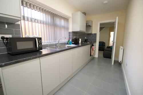 a kitchen with a sink and a microwave on a counter at Hastings Manor - Free Netflix, Parking, WiFi & Private Garden in Coventry