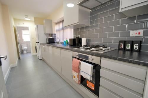 a kitchen with a stove and a counter top at Hastings Manor - Free Netflix, Parking, WiFi & Private Garden in Coventry
