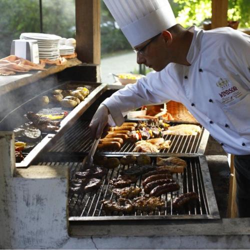 a chef is cooking food on a grill at Okay One Hotel in Phumi Ta Phul