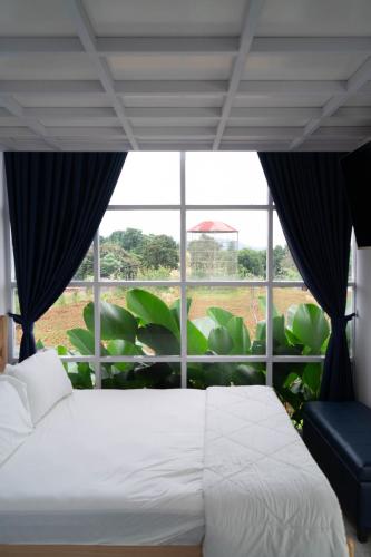 a bedroom with a white bed and a large window at SIP Garden Villa in Cibeuteung Udik