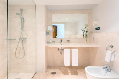 a bathroom with a shower and a sink and a mirror at Hipotels Playa La Barrosa - Adults Only in Chiclana de la Frontera