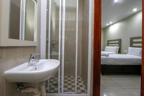 a bathroom with a sink and a shower and a bed at PLM Lodge in Durban
