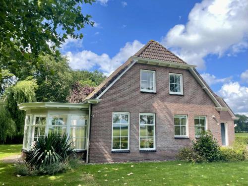 a brick house with white windows on a lawn at Enjoy the space and countryside at Het Hofhuys in Oosterwolde
