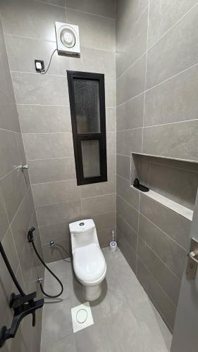 a bathroom with a toilet and a window on the wall at شقة أنيقة بصالة وغرفة نوم مع جلسة خارجية in Abha