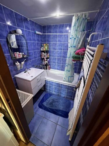 Un baño con azulejos azules, bañera y lavabo. en Útulný byt blízko centra, en Trenčín