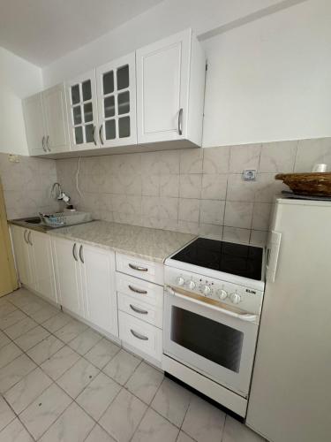 a white kitchen with a stove and a refrigerator at Peace in the heart of downtown in Pančevo