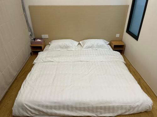 a large white bed in a room with two tables at 屋顶民宿 in Harbin