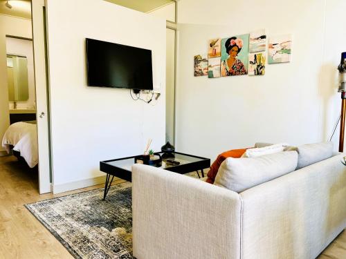 a living room with a white couch and a flat screen tv at Urban Luxe Stay - 5 Min to Gautrain & Parking in Johannesburg
