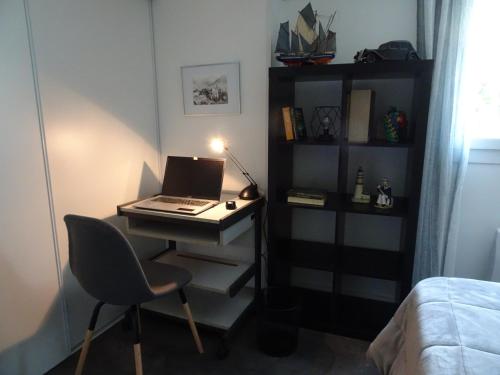 a desk with a laptop and a chair in a room at Le jardin de Brigitte in Vergeroux