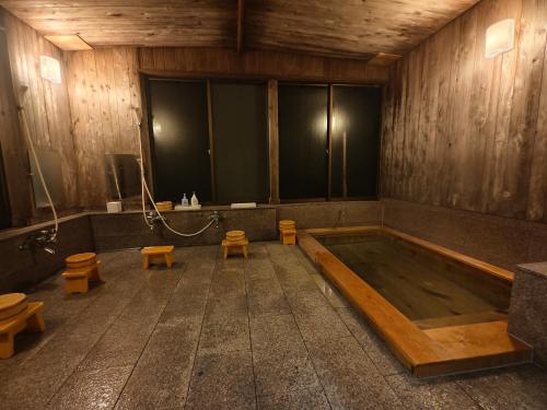 a bath room with a tub and some toilets at 旅館青柳 海越し立山連峰の雪山絶景で休もう in Himi