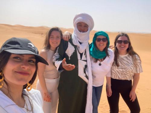 a group of women standing in the desert at Safari luxury camp in Merzouga
