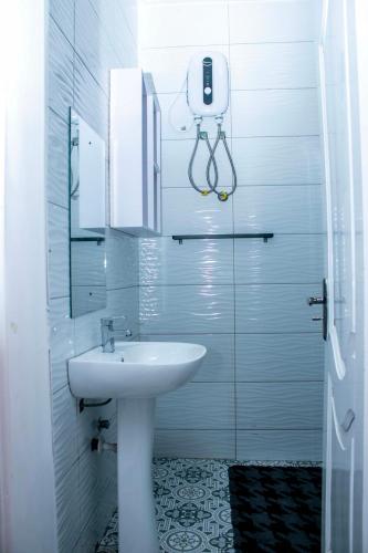 a white bathroom with a sink and a mirror at Luxurious Akwaaba Villa in Kwesimintim