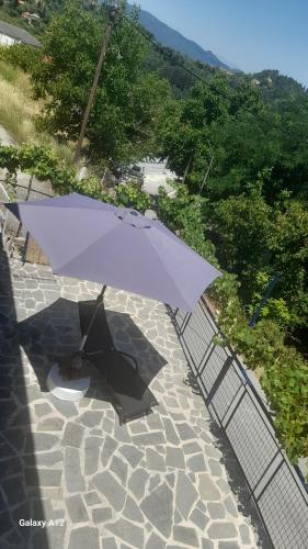 a purple umbrella sitting on top of a stone patio at Rahati in Pramanta - Ραχάτι στου Τσακτσίρα in Pramanta