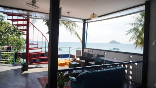 a room with a balcony with a view of the ocean at Scuba Square Hostel in Koh Tao