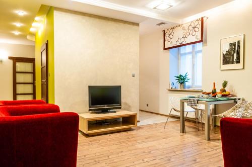 a living room with a television and a table with chairs at Home & Travel Apartments - AC - Parking - City Centre - Manufaktura - OFF Piotrkowska - EC1 - ATLAS Arena - Orientarium - Monopolis in Łódź