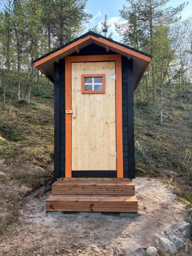 a out house with a wooden door in a field at Villa Aiku in Leppäjärvi