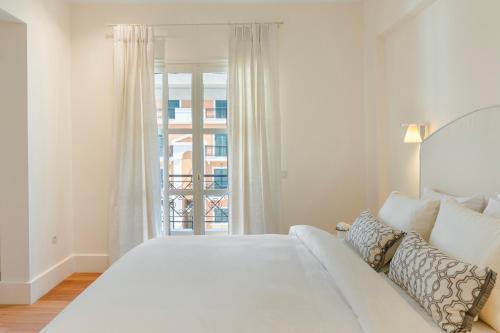 a white bedroom with a large bed and a window at Etoile Luxury Suites in Argostoli