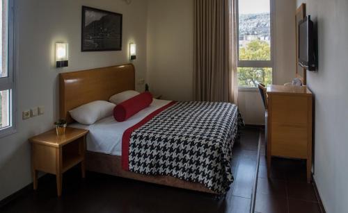 a bedroom with a bed with two pillows and a window at Astoria Galilee Hotel in Tiberias
