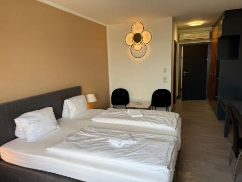 ein Hotelzimmer mit zwei Betten und zwei Stühlen in der Unterkunft Skycity Hotel Atrigon in Klagenfurt am Wörthersee
