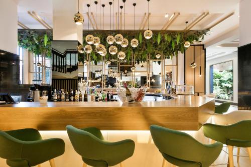 a bar with green chairs in a restaurant at Melia Barajas in Madrid