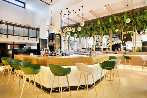 a bar in a restaurant with green chairs at Melia Barajas in Madrid