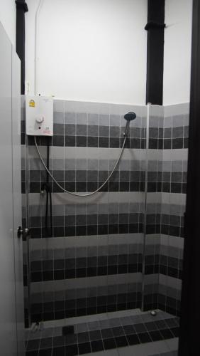 a shower in a bathroom with black and white tile at Scuba Square Hostel in Koh Tao