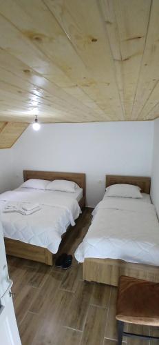 two beds in a room with wooden ceilings at Bujtina Sherifaj in Valbonë