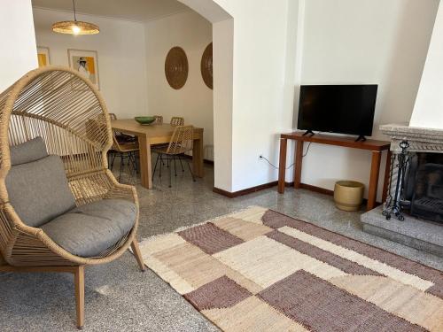a living room with a chair and a television at Casa Na Vila in Vila Pouca de Aguiar