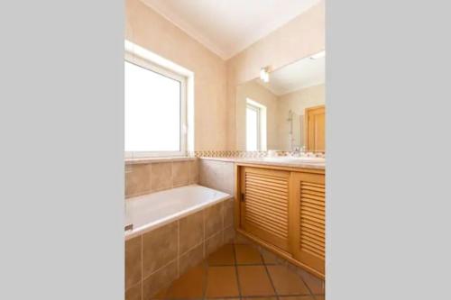 a bathroom with a tub and a sink and a mirror at T2 piscina e vista mar Praia del Rey Óbidos A6 in Casal da Lagoa Seca