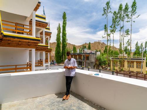 a man standing on a wall looking at his cell phone at Hotel Bayshu - The Hosteller Leh in Leh