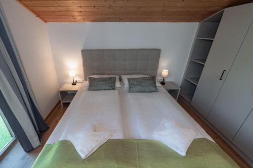 a large white bed in a room with two lamps at Lake Resort Pressegger See in Hermagor