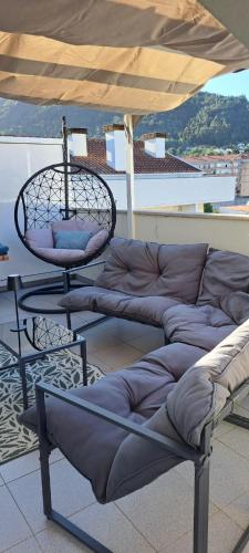 a couch and a chair under an umbrella on a roof at Chez Louise: onde a Serra beija o Céu in Lousã