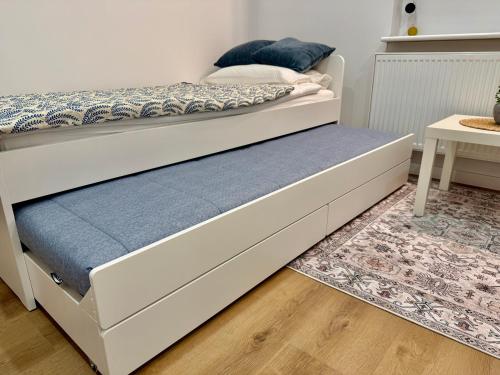 a white bed with a blue mattress and a table at Nowoczesny Dom z Ogrodem w Warszawie 'NOWY OBIEKT' in Warsaw