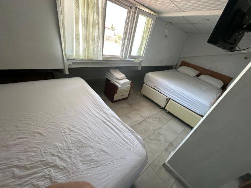 a small bedroom with two beds and a television at Nr1 Pansiyon in Canakkale