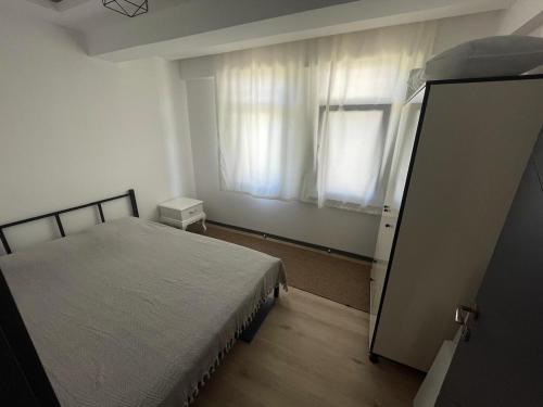 a bedroom with a bed and a window with curtains at Spacious and modern apartment with a view in Gökçeada