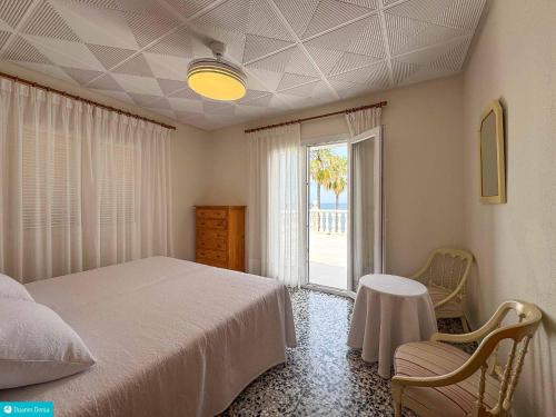 een slaapkamer met een bed, een tafel en een raam bij casa frente el mar in Denia