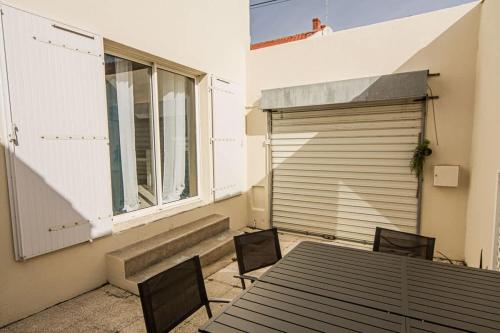 un patio avec une table et des chaises ainsi qu'un garage dans l'établissement Jolie maison de ville La Rochelle, à La Rochelle