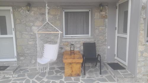 a porch with a hammock and a chair and a building at Rahati in Pramanta - Ραχάτι στου Τσακτσίρα in Pramanta