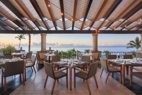 a restaurant with tables and chairs with the ocean in the background at Hacienda del Mar Los Cabos, an Autograph Collection All-Inclusive Resort in Cabo San Lucas