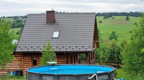 a house with a swimming pool in front of it at Domki Na Wzgórzu in Nowica