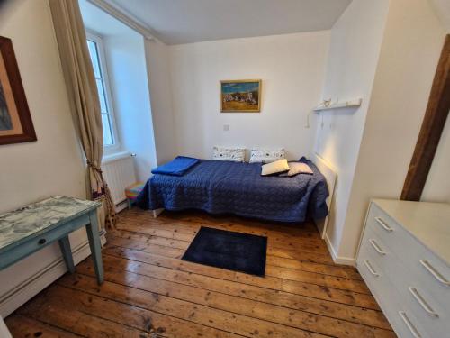 a small bedroom with a blue bed and a wooden floor at La Planche, in Avranches