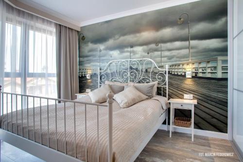 a bedroom with a bed with a painting of a pier at Horyzont Luksusowe apartamenty nad morzem z parkingiem Międzyzdroje in Międzyzdroje
