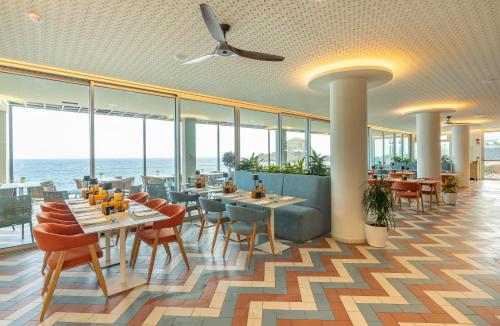 a restaurant with tables and chairs and the ocean at Aqua Natura Madeira in Porto Moniz