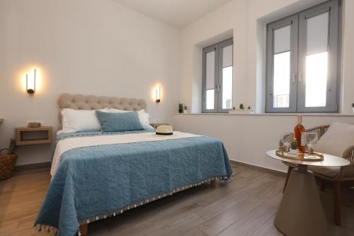 a bedroom with a bed with a blue blanket and two windows at Casa di Lou in Ermoupoli