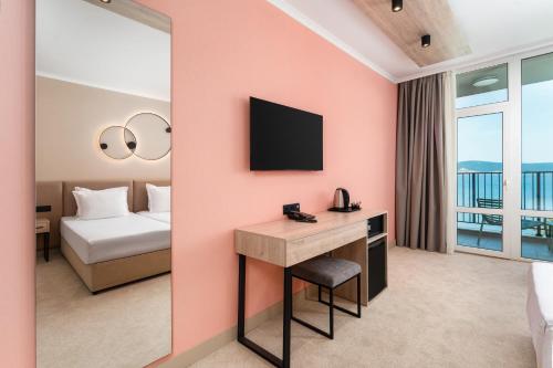 a hotel room with a desk and a bed and a television at Festa Panorama Hotel in Nesebar