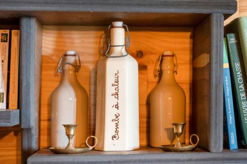 three wine bottles sitting on a shelf with cups at L'Escale du Dernier Pin in Escalans